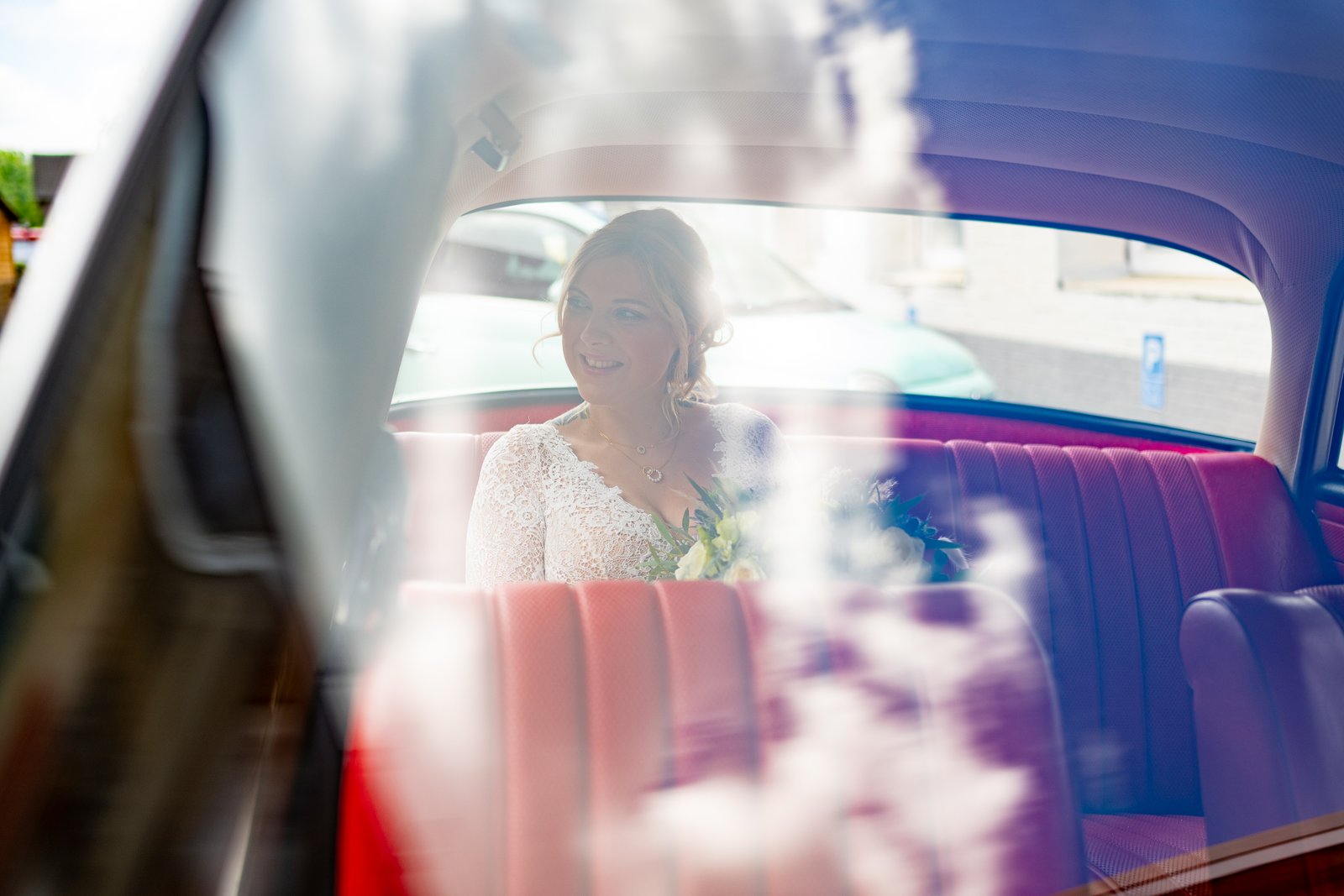 Sophie und Björn in einer Spiegelung am Oldtimer an ihrem Hochzeitstag.